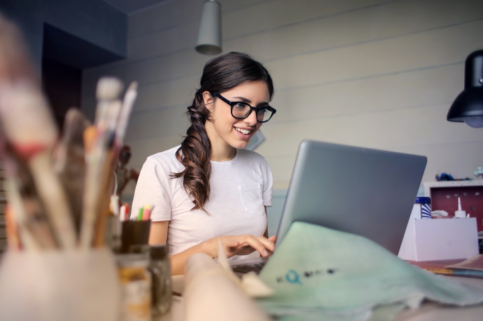 Young woman wearing glasses and white t-shirt working on laptop. 